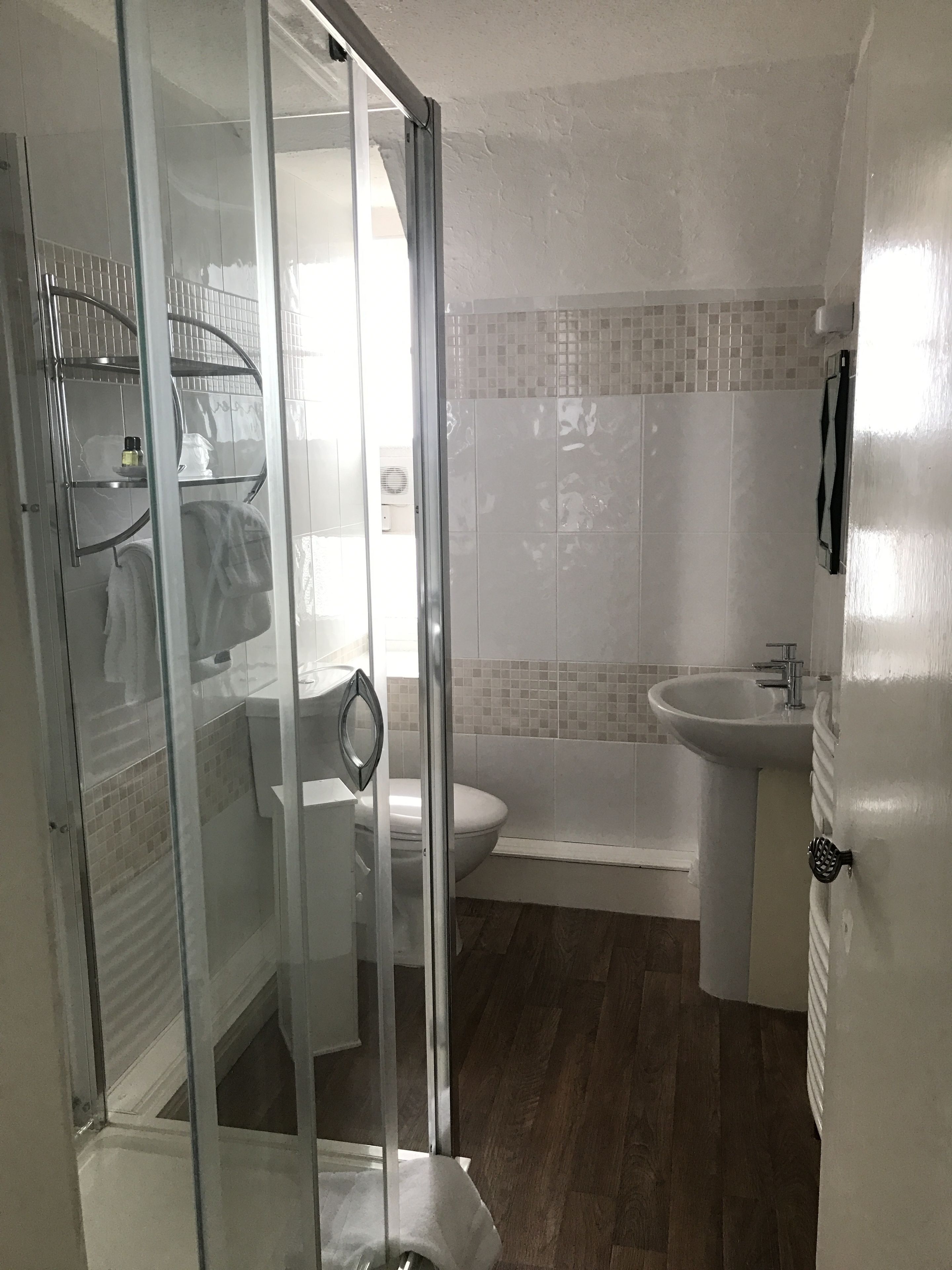A bathroom with a glass shower enclosure, a toilet, a bathtub, and a sink.