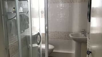 A bathroom with a glass shower enclosure, a toilet, a bathtub, and a sink.
