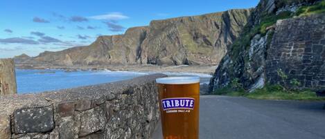 Una cerveza en una mesa de madera con vista al mar.