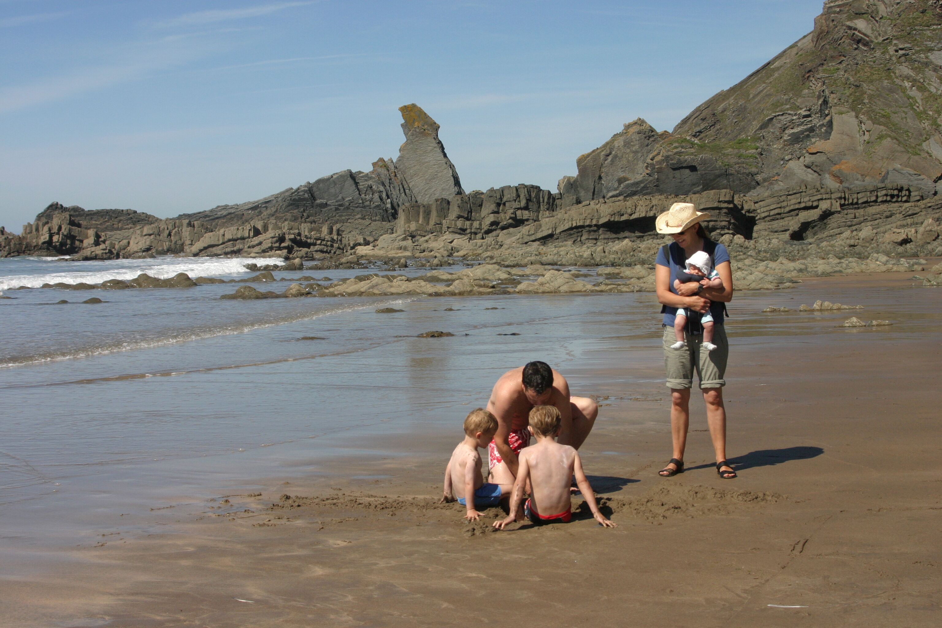 A sandy beach with rocky formations in the background.