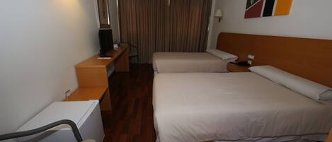 A hotel room with two beds, a desk, a chair, a television, and a curtain.