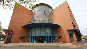 Un hotel con fachada curva, amplias ventanas y una entrada destacada.