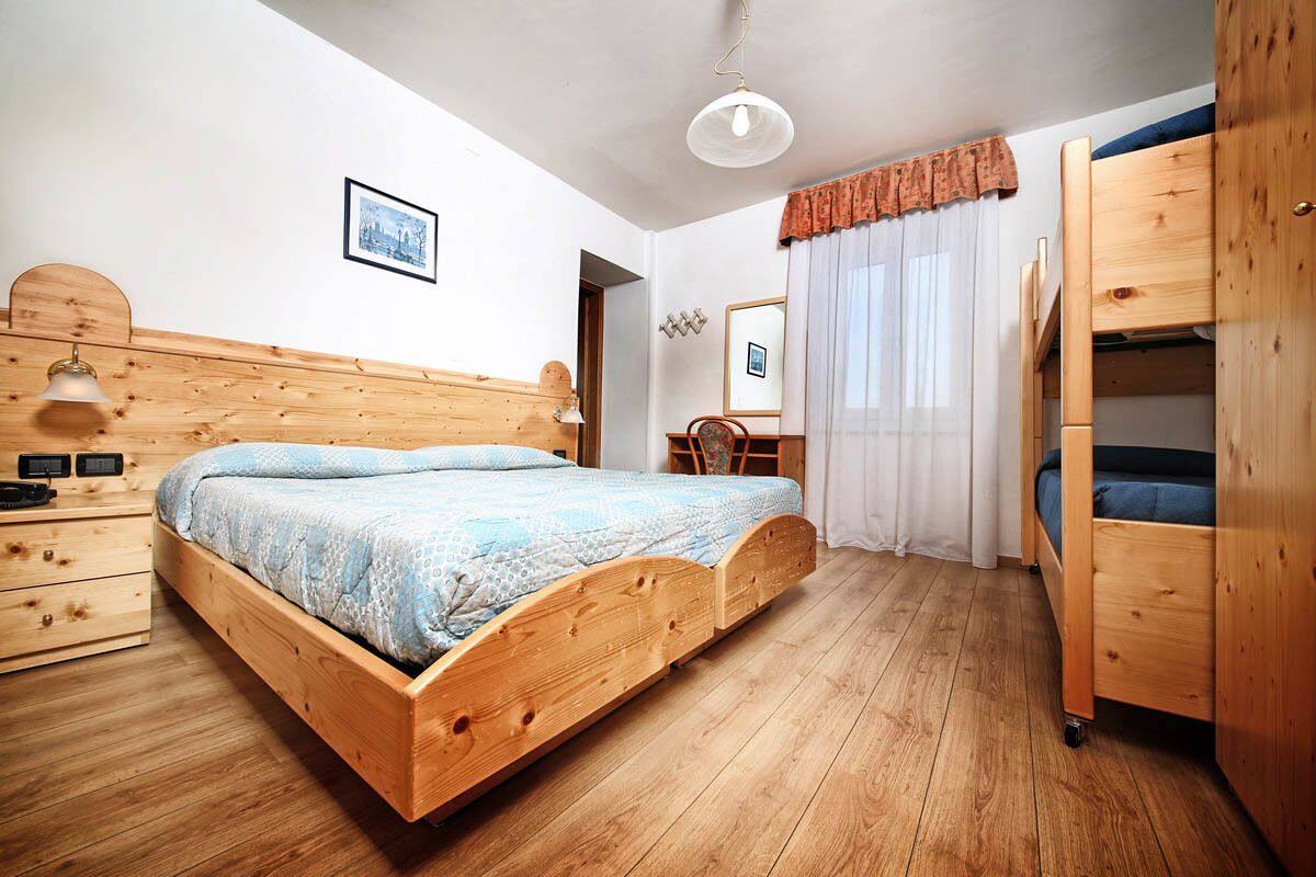 Een houten bed met hoofdeinde, nachtkastje, spiegel en garderobe.