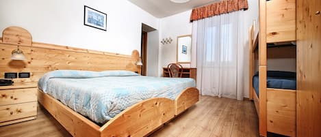 A wooden bed with a headboard, a bedside table, a mirror, and a wardrobe.