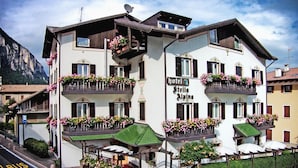 A hotel with balconies adorned with flowers, a green roof, and a sign indicating it is a hotel. - Hotel Stella Alpina (Fai della Paganella)