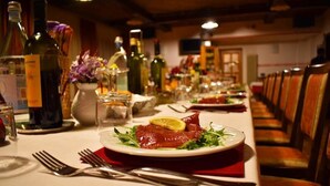 A dining table set with plates of food, wine bottles, and glasses. - Hotel Stella Alpina (Fai della Paganella)