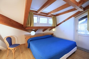 Une chambre à coucher avec un lit, une chaise, un bureau et une fenêtre.