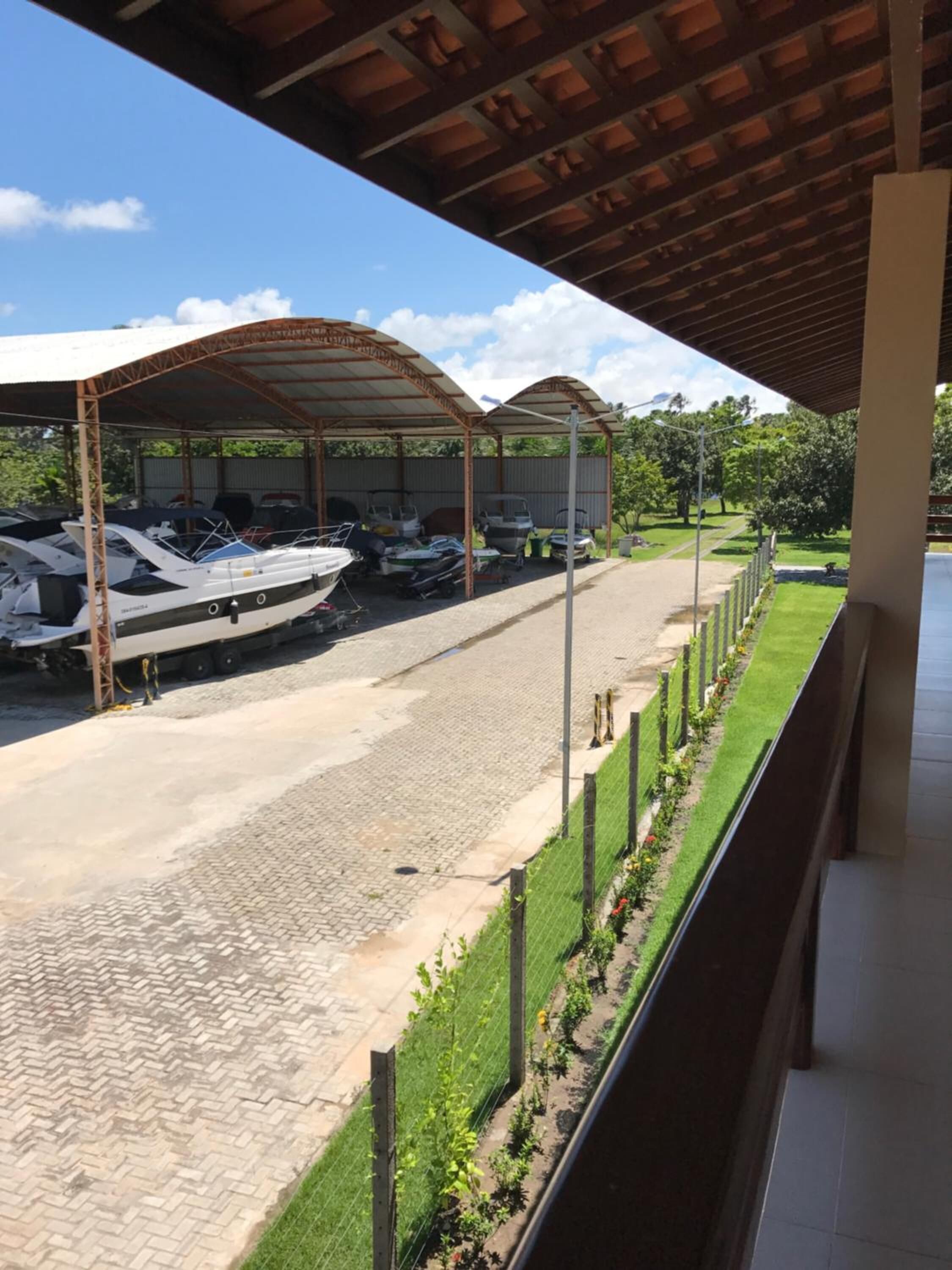 A covered boat storage area with boats and a paved walkway.