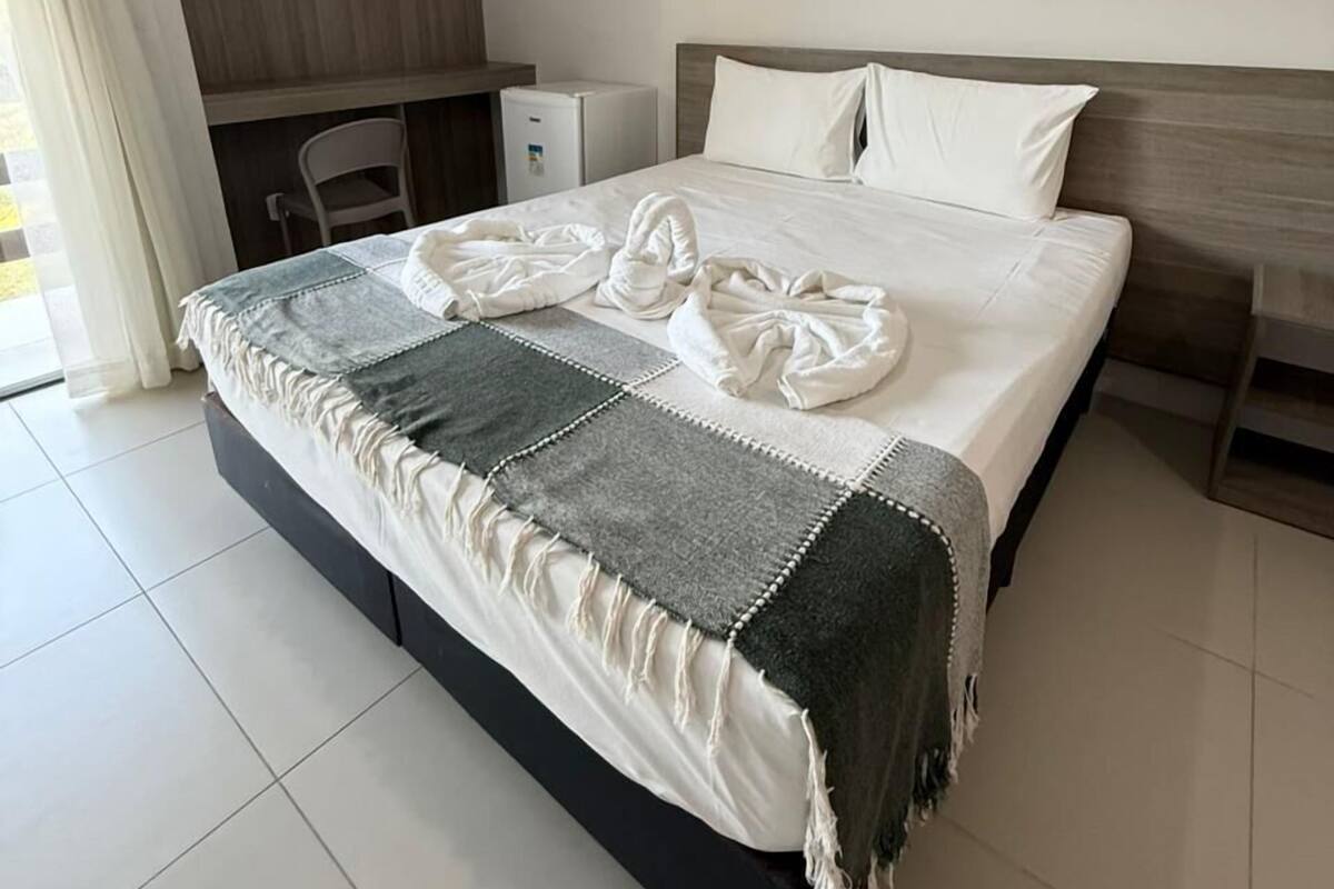 A hotel room with a bed, a desk, and a chair.