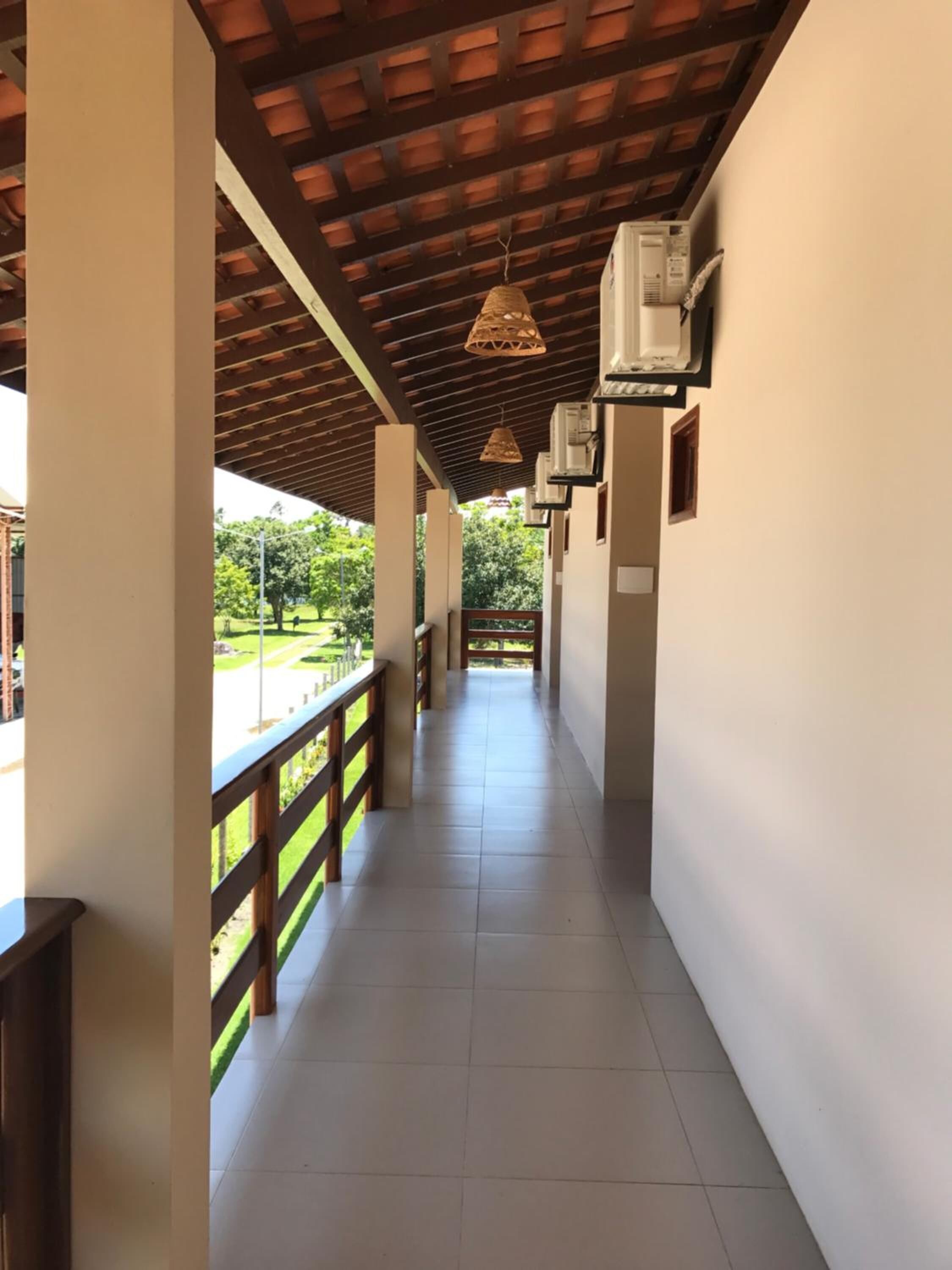 Un pasillo con suelo de baldosas, barandillas de madera y techo con estructura de vigas de madera.