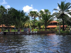 A waterfront property with a wooden fence, palm trees, and a building with a red roof.