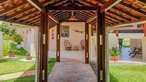 A covered outdoor area with a brick pathway leading to a seating area with chairs and a table. - Portal do Sol Lençóis Pousada (Barreirinhas)