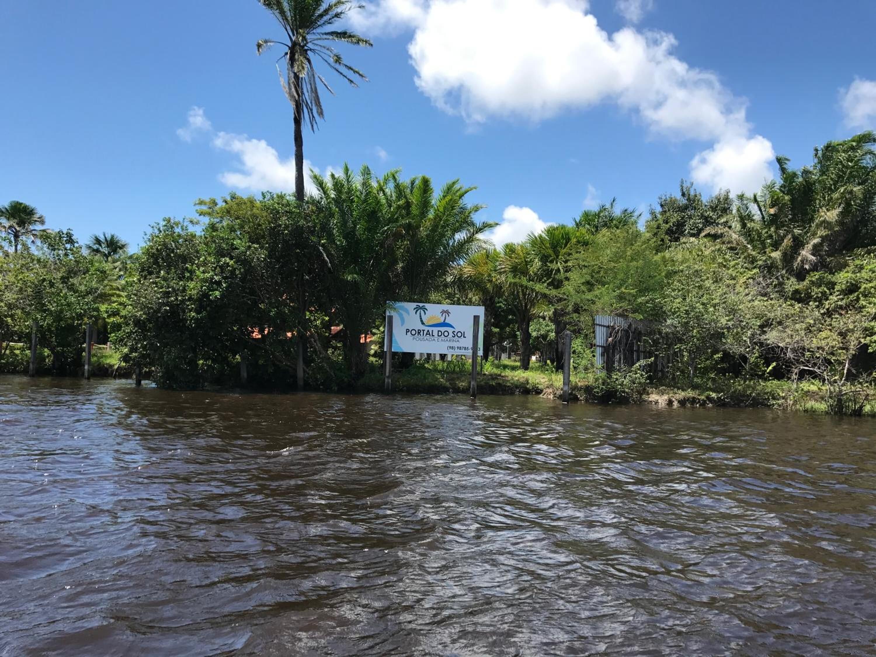 A sign for 'Portal do Sol' with a palm tree and dense foliage in the background.