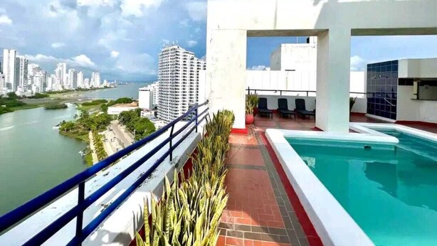 A rooftop pool area with a view of a river and city skyline. - Edificio Marina del Rey (Cartagena)
