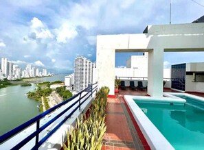 A rooftop pool area with a view of a river and city skyline. - Edificio Marina del Rey (Cartagena)