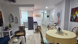 A modern living room with a dining area, featuring a checkered tablecloth, wicker furniture, and artwork on the walls. - Edificio Marina del Rey (Cartagena)