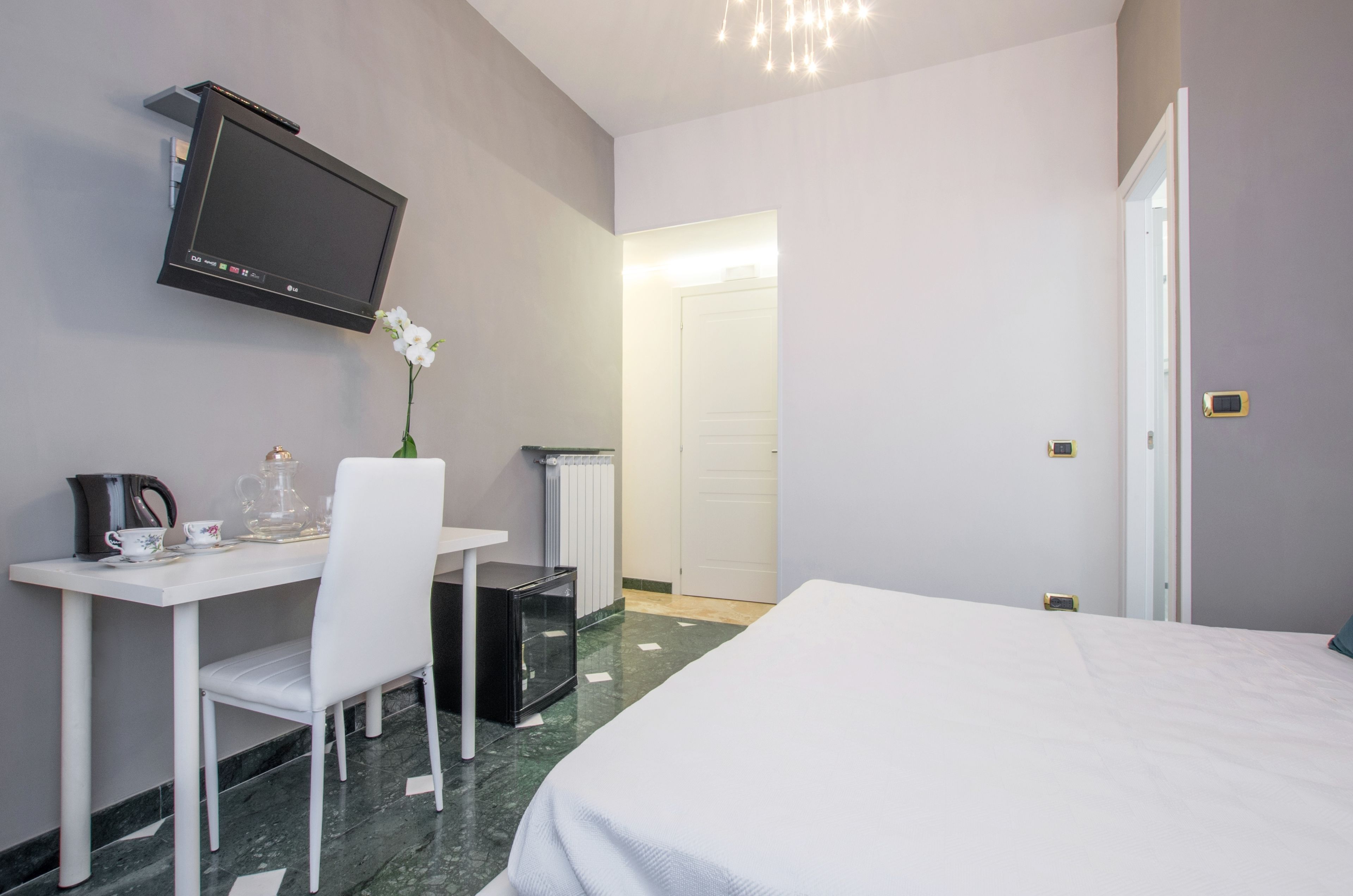 Une chambre d’hôtel comprenant un lit, un bureau avec une chaise, un téléviseur fixé au mur et un radiateur.