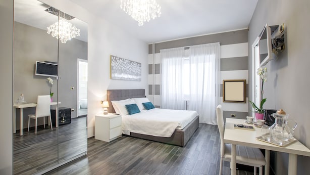 A modern bedroom with a large bed, bedside tables, a desk, and a mirror. - Trastevere Sweet House (Rome)
