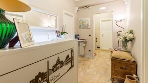 A reception area with a counter, framed pictures, a green vase, and a wall-mounted painting. - Trastevere Sweet House (Rome)