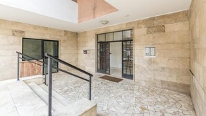 A modern interior with a stone floor, a staircase with metal railings, and a large glass door leading to another room. - Trastevere Sweet House (Rome)