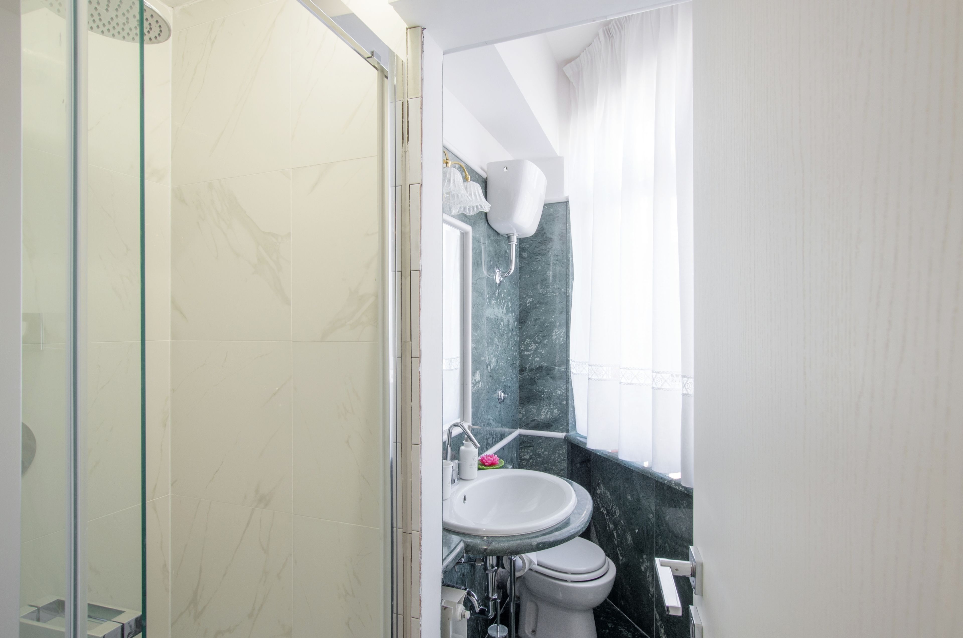 A bathroom with a glass-enclosed shower, a sink, and a toilet.