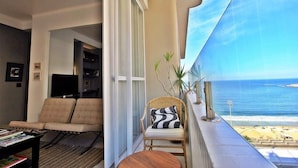 A balcony with a view of the ocean, a wicker chair, a sofa, and a small table. - Rio Spot Begossi (Rio de Janeiro)