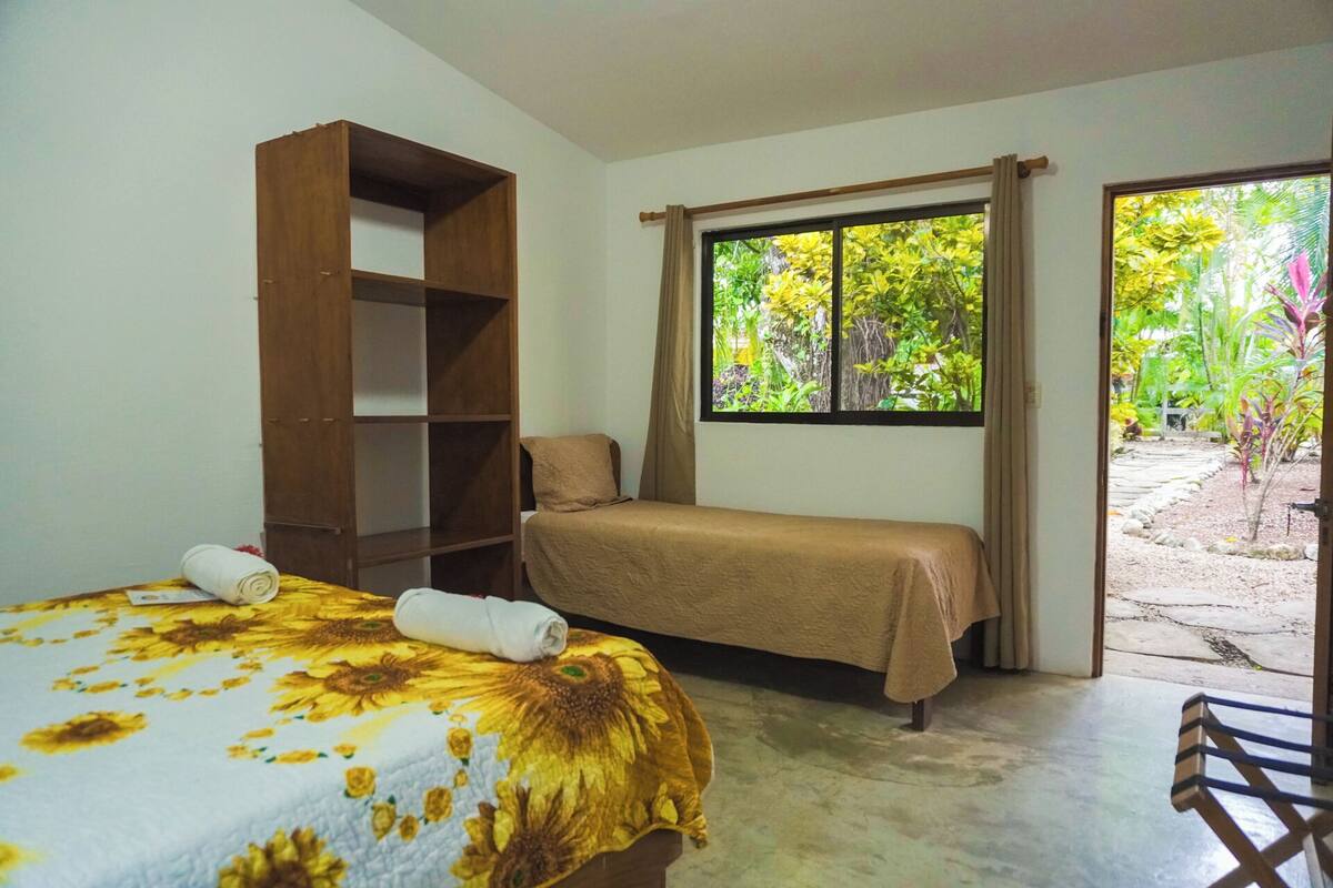Ein Zimmer mit einem Bett, einem Holzregal und einem Fenster mit Blick auf Grünflächen.
