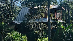 Un edificio con techo de metal y estructura de madera, rodeado de árboles y césped.
