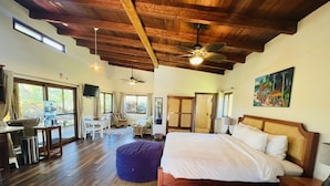Una habitación amplia con una cama grande, techo de madera y vistas al exterior.