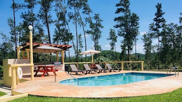 Una piscina al aire libre, sillones reclinables de piscina