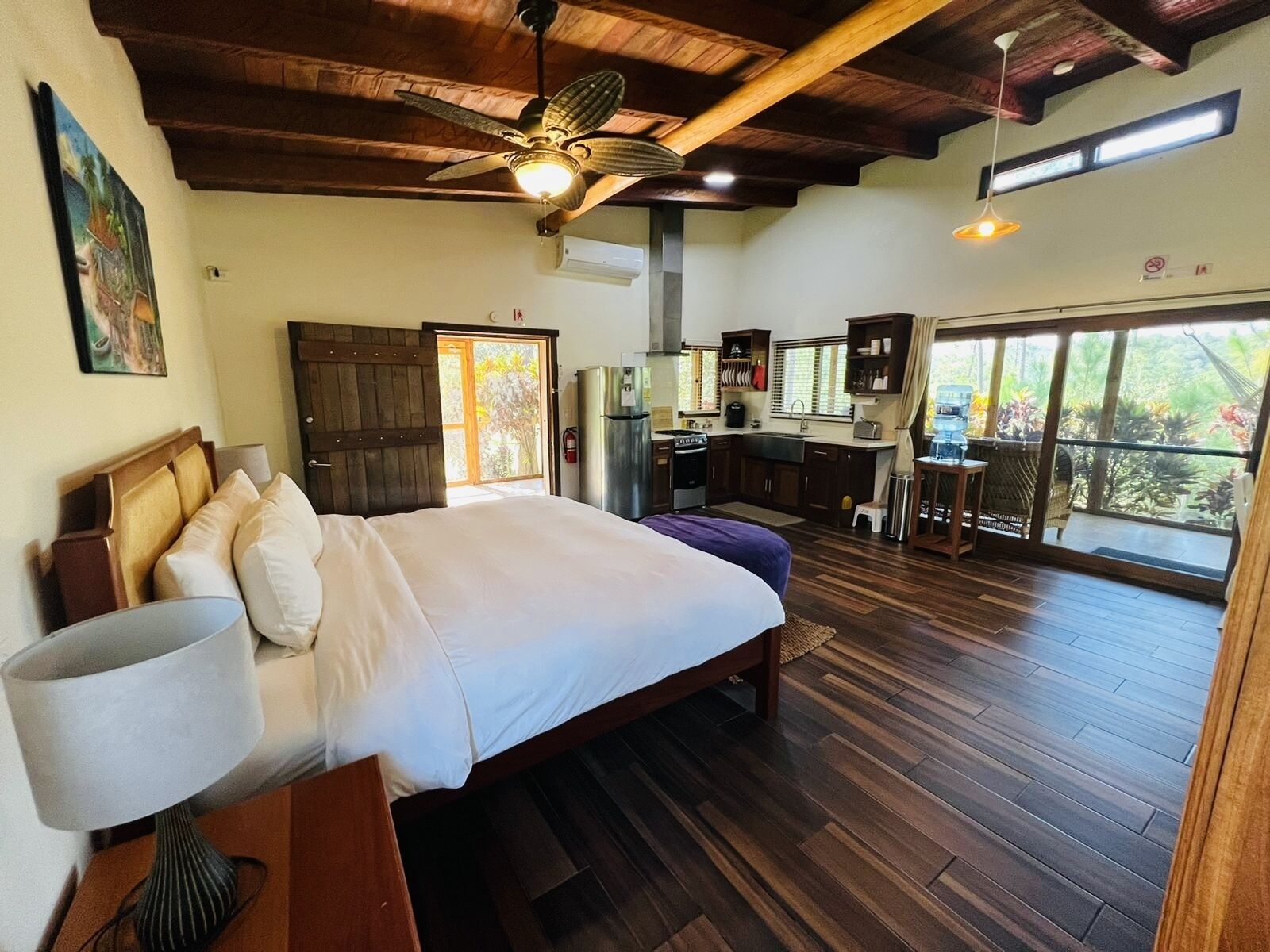 A spacious bedroom with a large bed, a ceiling fan, and a view of the outdoors through a sliding door.