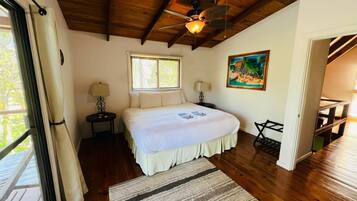 A bedroom with a wooden ceiling, a bed with a white bedspread, a window with blinds, a painting on the wall, and a wooden floor.