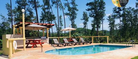 Una piscina al aire libre, sombrillas, tumbonas