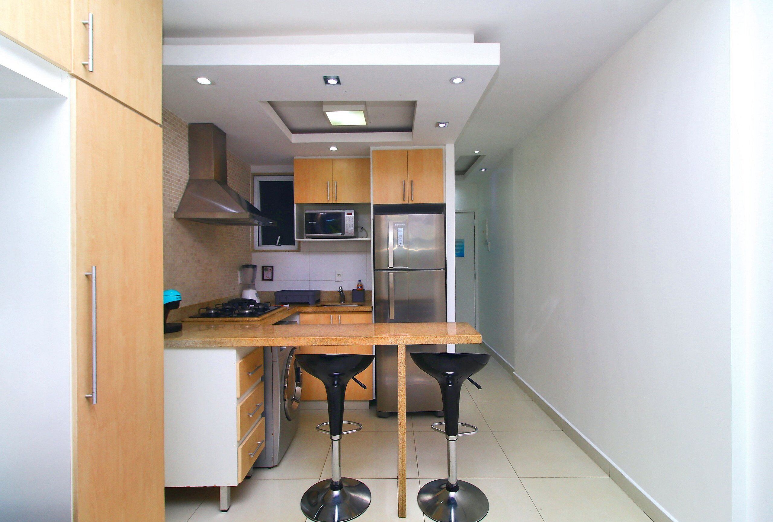 A modern kitchen with wooden cabinets, stainless steel appliances, and a central island with bar stools.