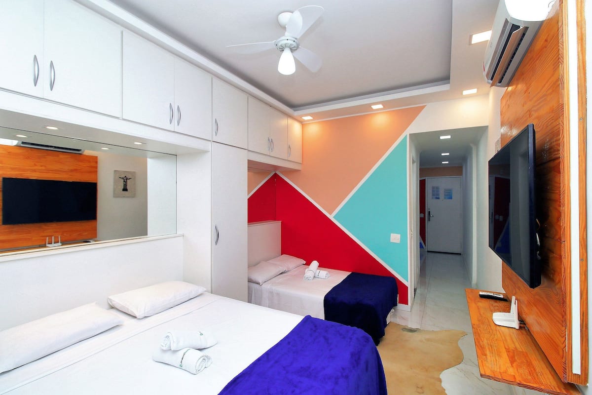 A hotel room with two beds, a TV, and a ceiling fan.