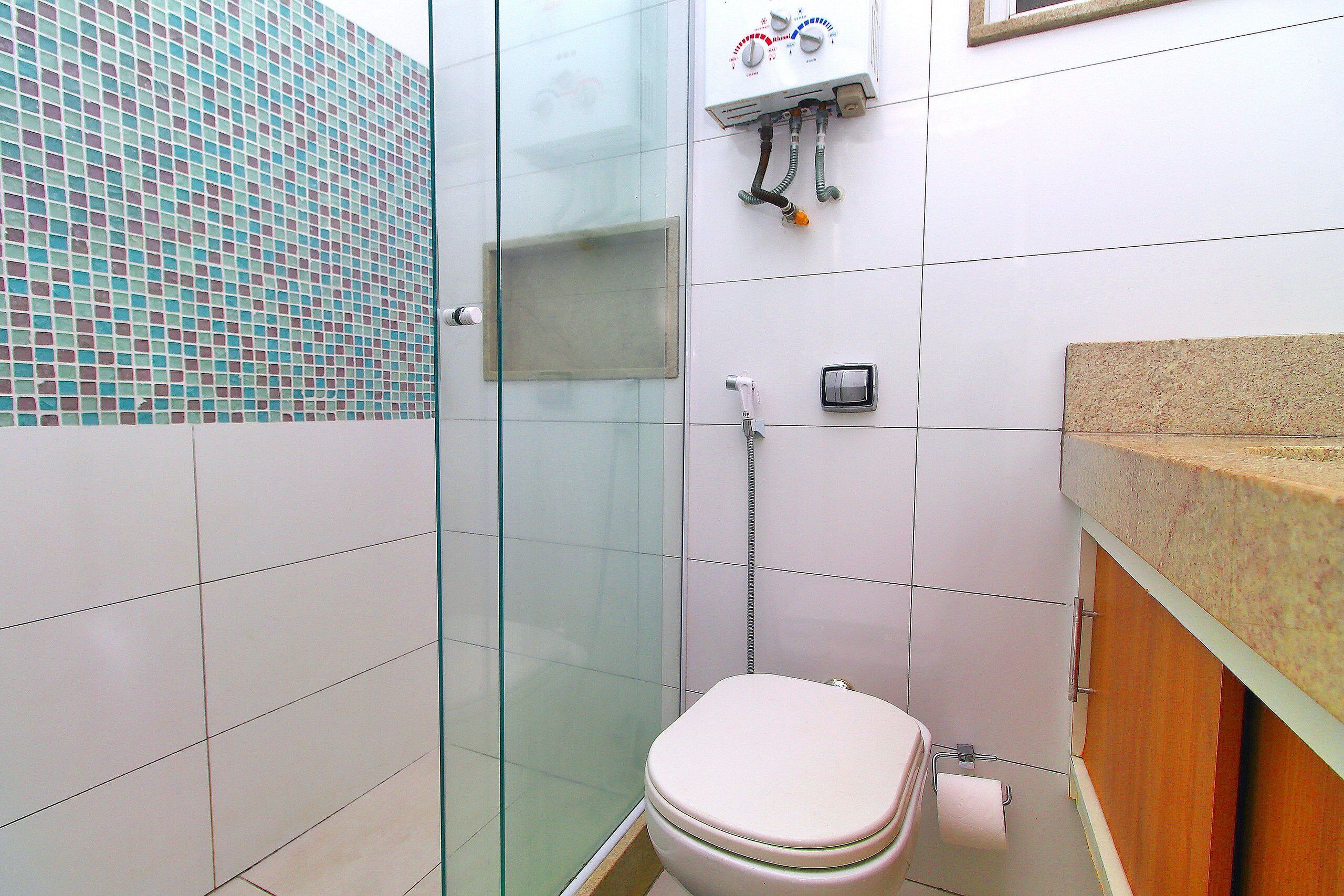 A bathroom with a glass shower enclosure, a toilet, and a sink with a granite countertop.