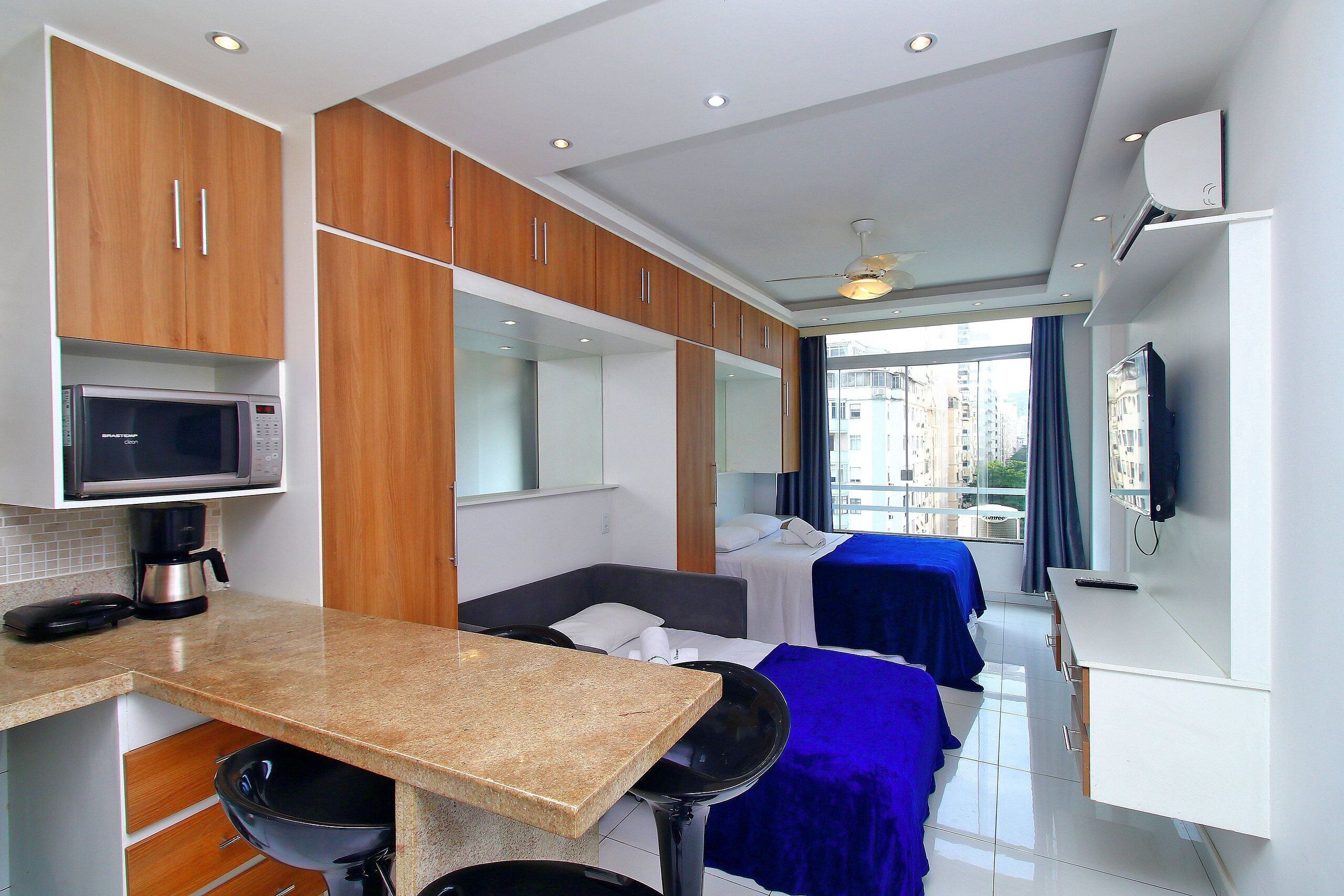 Habitación de hotel compacta con kitchenette, una cama, un escritorio y vista a la ciudad.