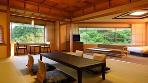 A traditional Japanese-style room with tatami flooring, a low table, and a sofa. - Akiu Grand Hotel (Sendai)