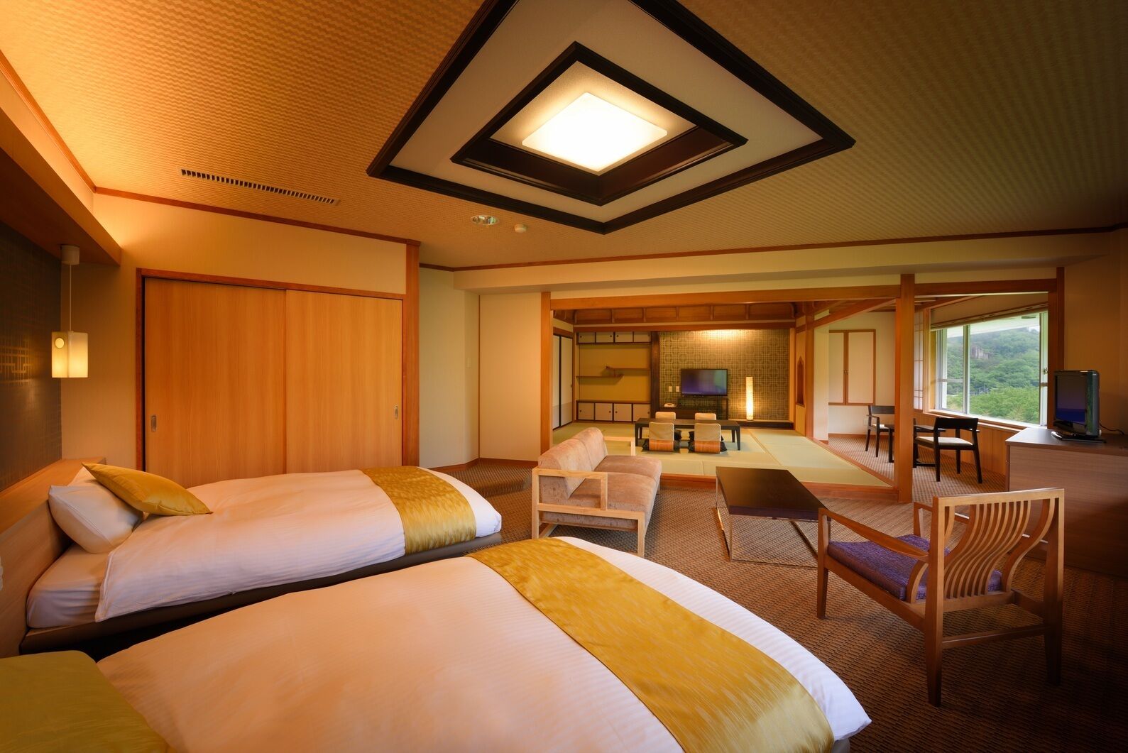 Ein Hotelzimmer mit zwei Betten, einer Sitzecke mit Fernseher und Blick ins Freie.