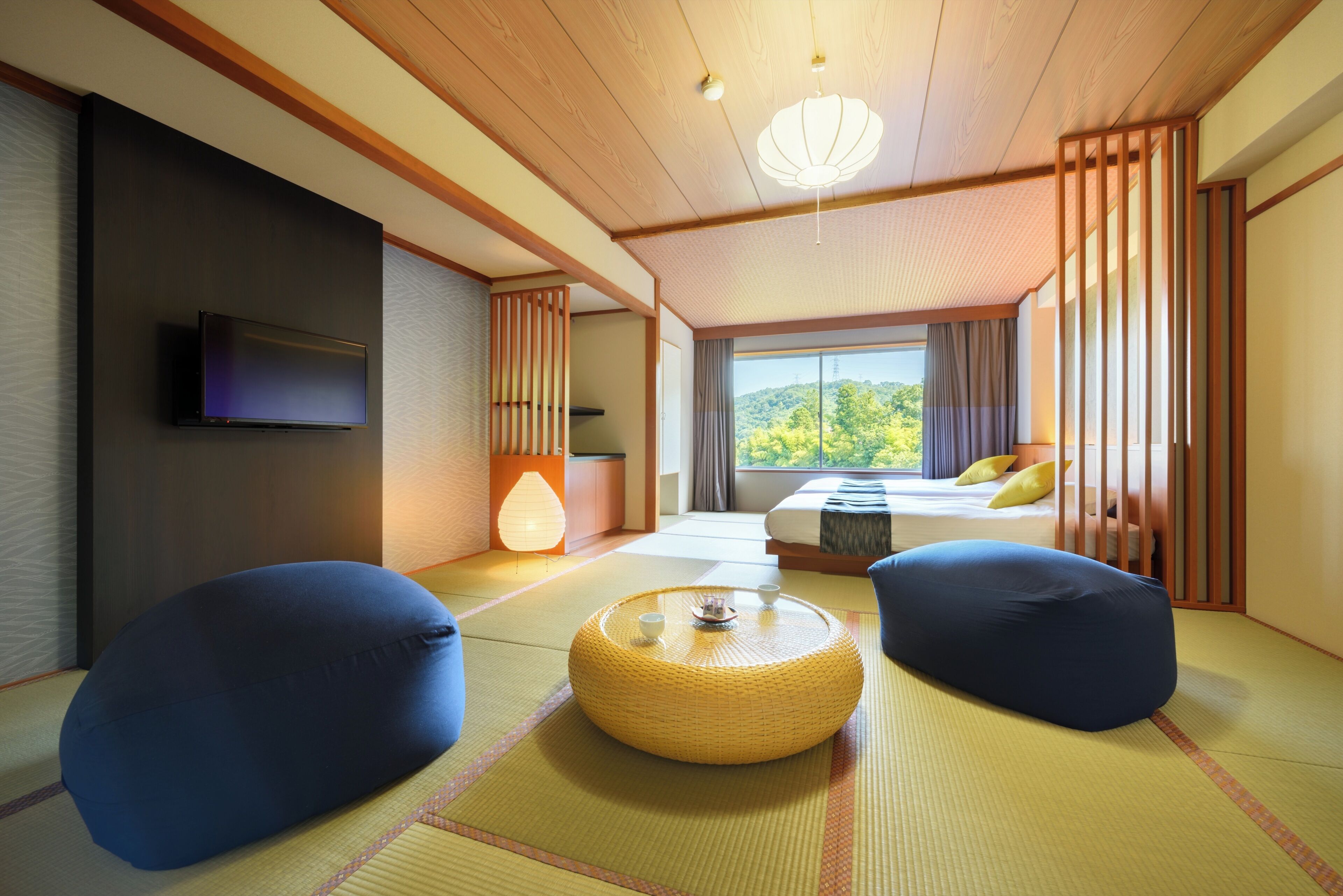Ein traditioneller japanischer Raum mit Tatami-Böden, einem niedrigen Tisch, zwei Sitzsäcken, einem Bett mit Aussicht und einem Fernseher.