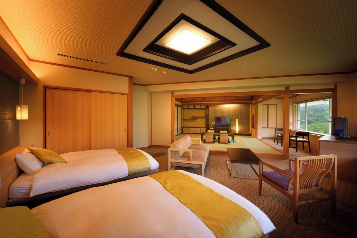 A hotel room with two beds, a seating area, and a television.