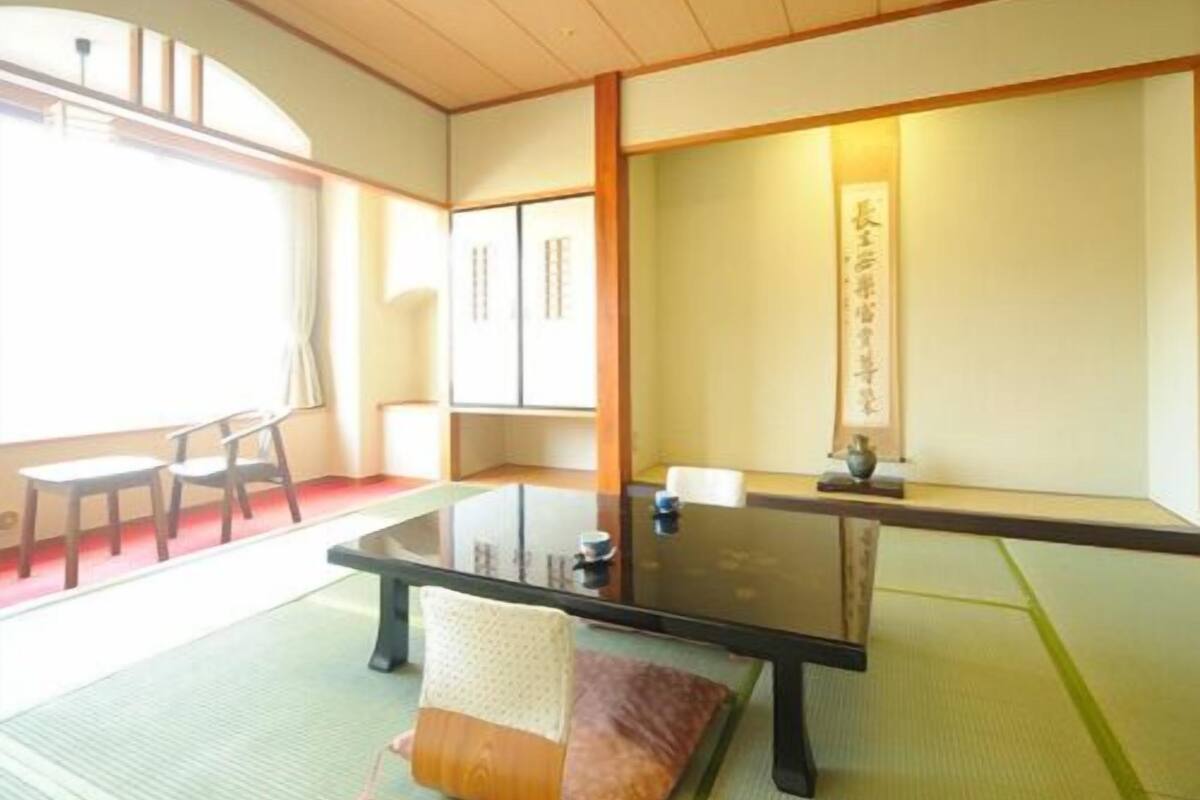 A traditional Japanese room with tatami flooring, a low table, and sliding doors.