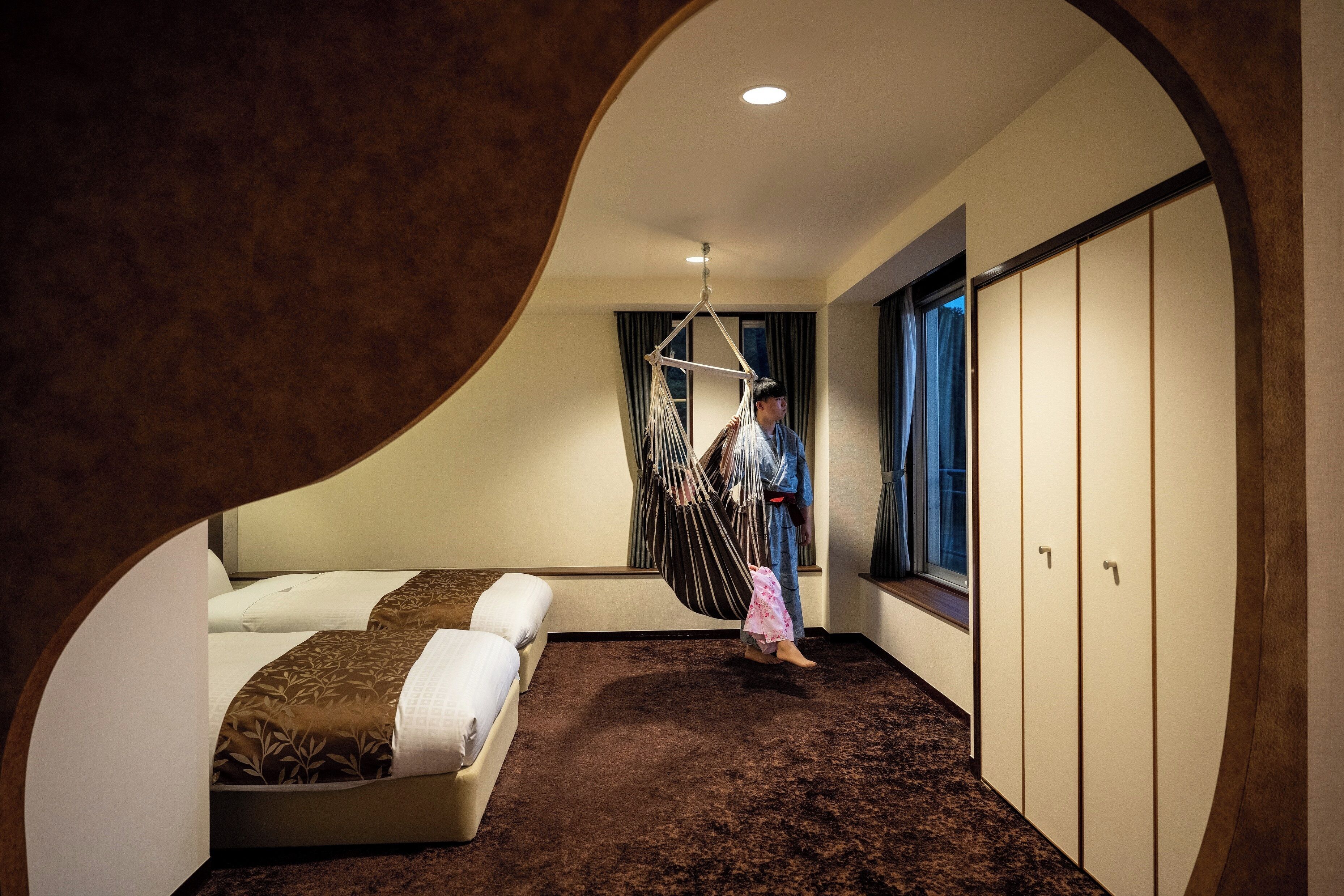 Ein Zimmer mit einem Bett, einem Hängesessel, einem Kleiderschrank und einem Fenster.