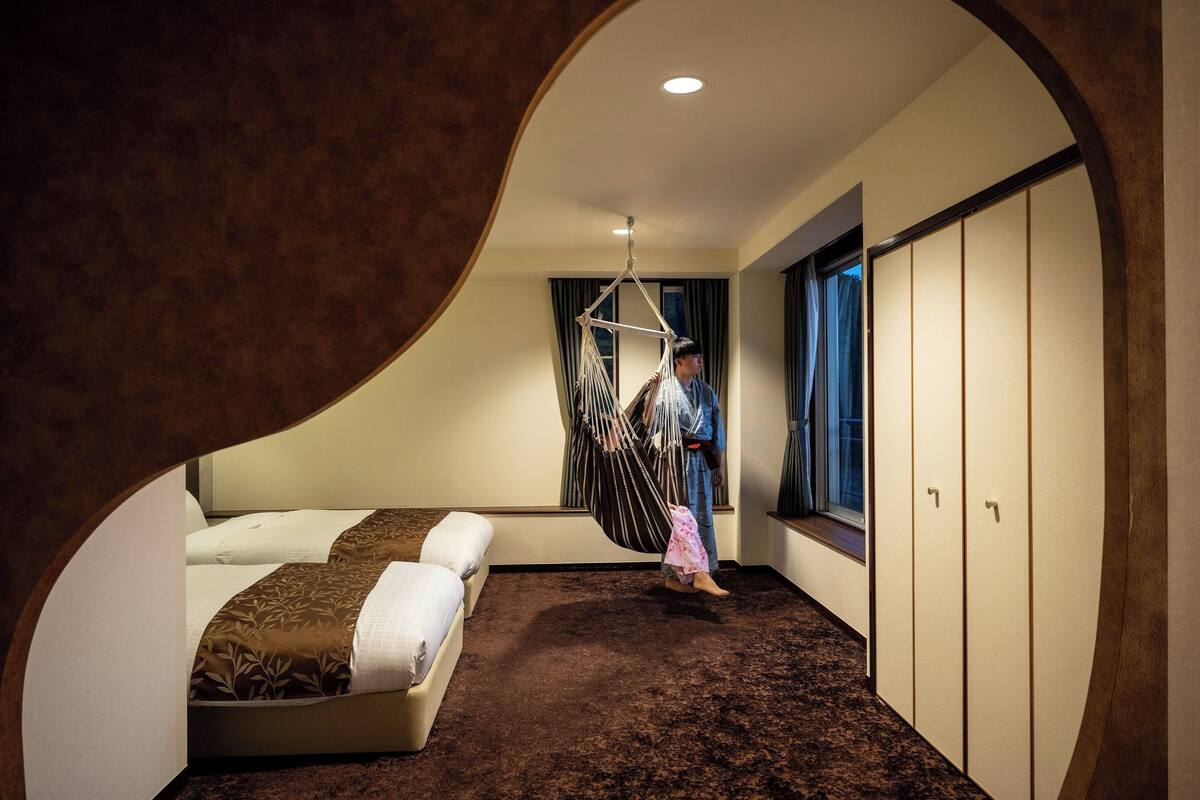 A room with a bed, a hanging chair, a wardrobe, and a window.