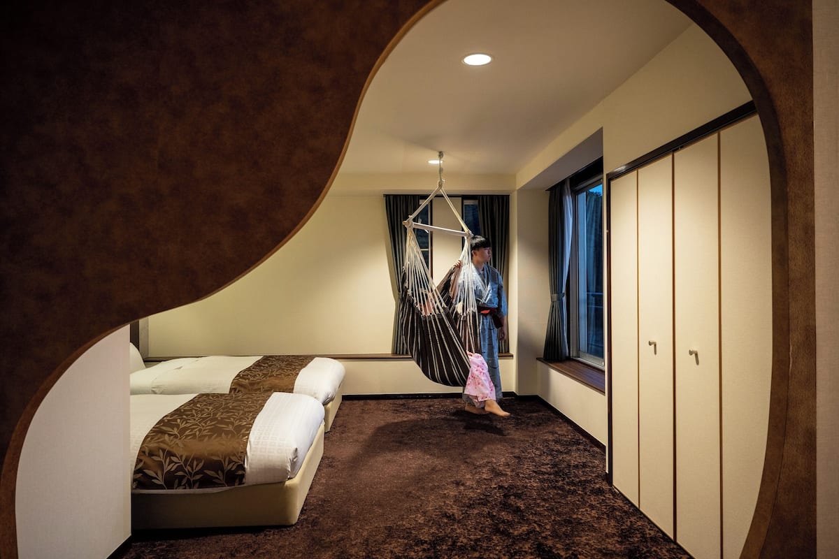 Ein Zimmer mit einem Bett, einem Hängesessel, einem Kleiderschrank und einem Fenster.