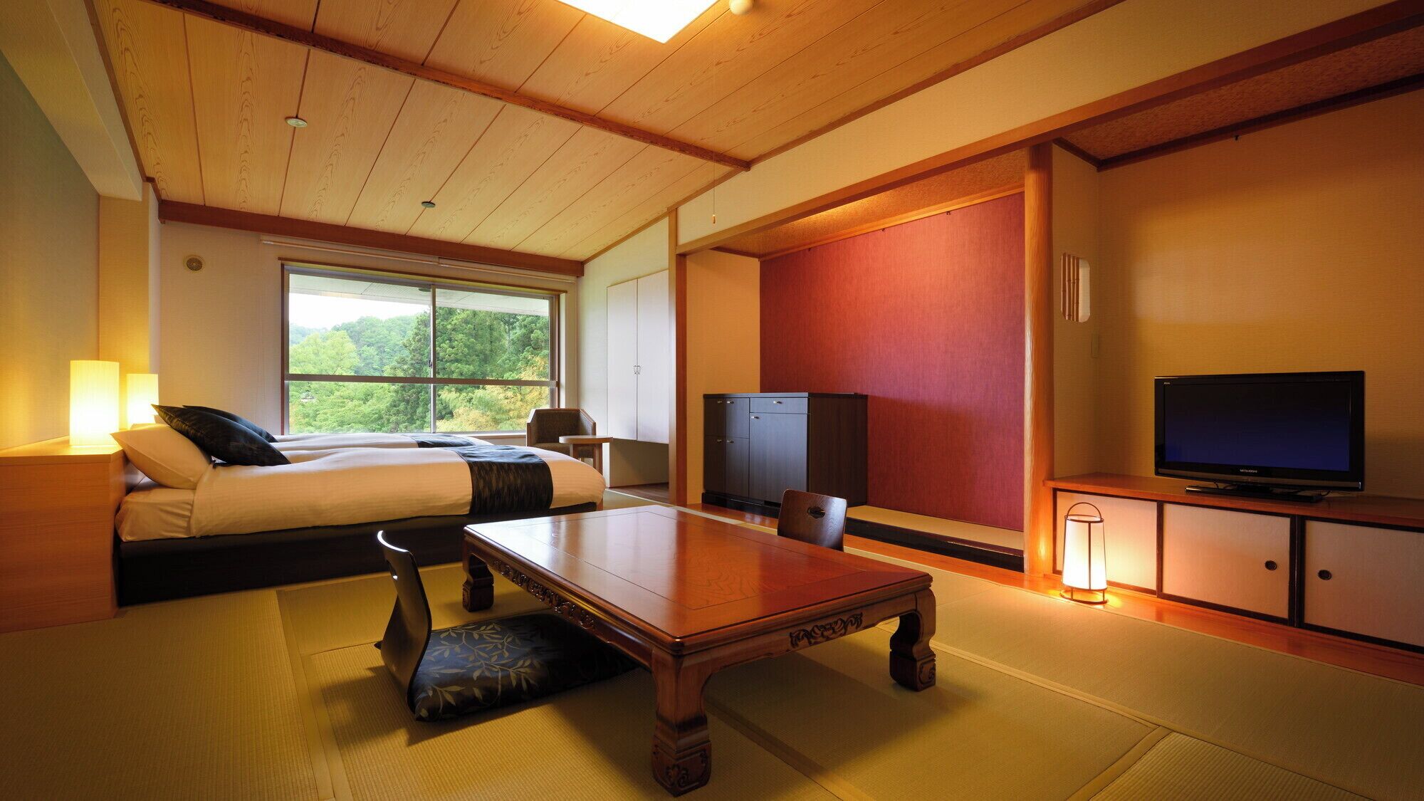Ein Hotelzimmer mit Bett, Schreibtisch, Fernseher und Blick ins Freie.