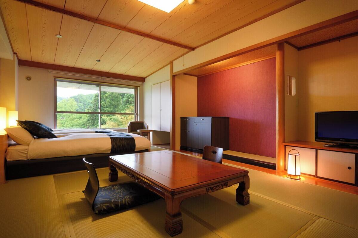A hotel room with a bed, a desk, a television, and a view of the outdoors.