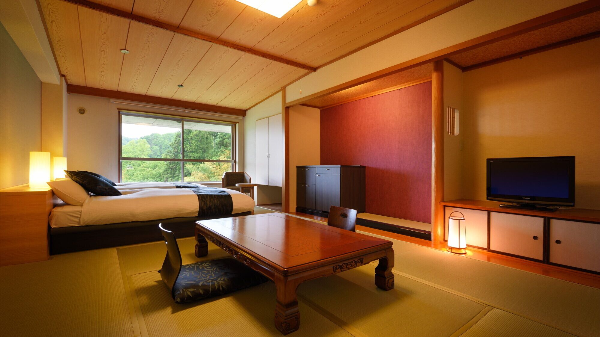 Ein Hotelzimmer mit Bett, Fernseher, einem Holztisch und Blick auf Grünfläche.