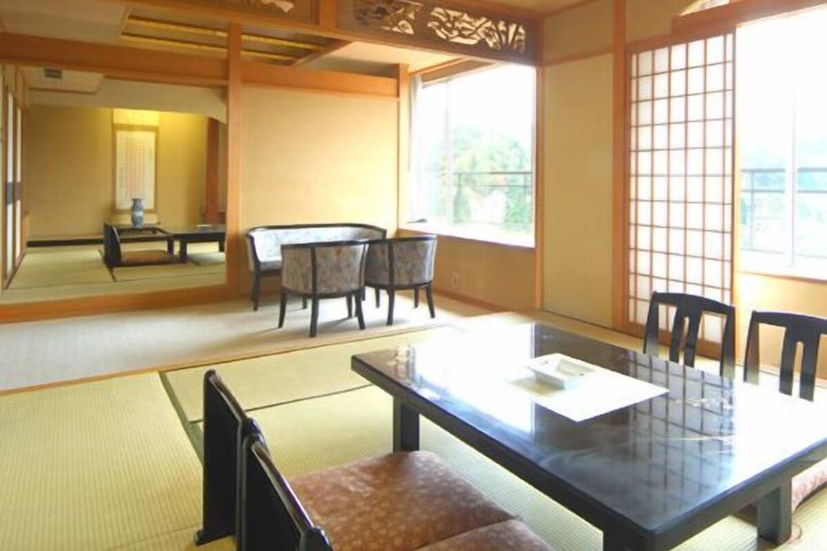 A traditional Japanese room with tatami flooring, a low table, and chairs.