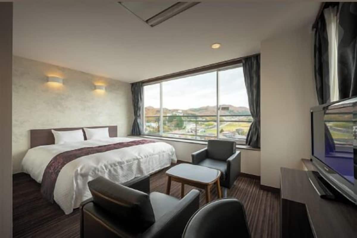 A hotel room with a bed, a TV, a desk, and a chair.